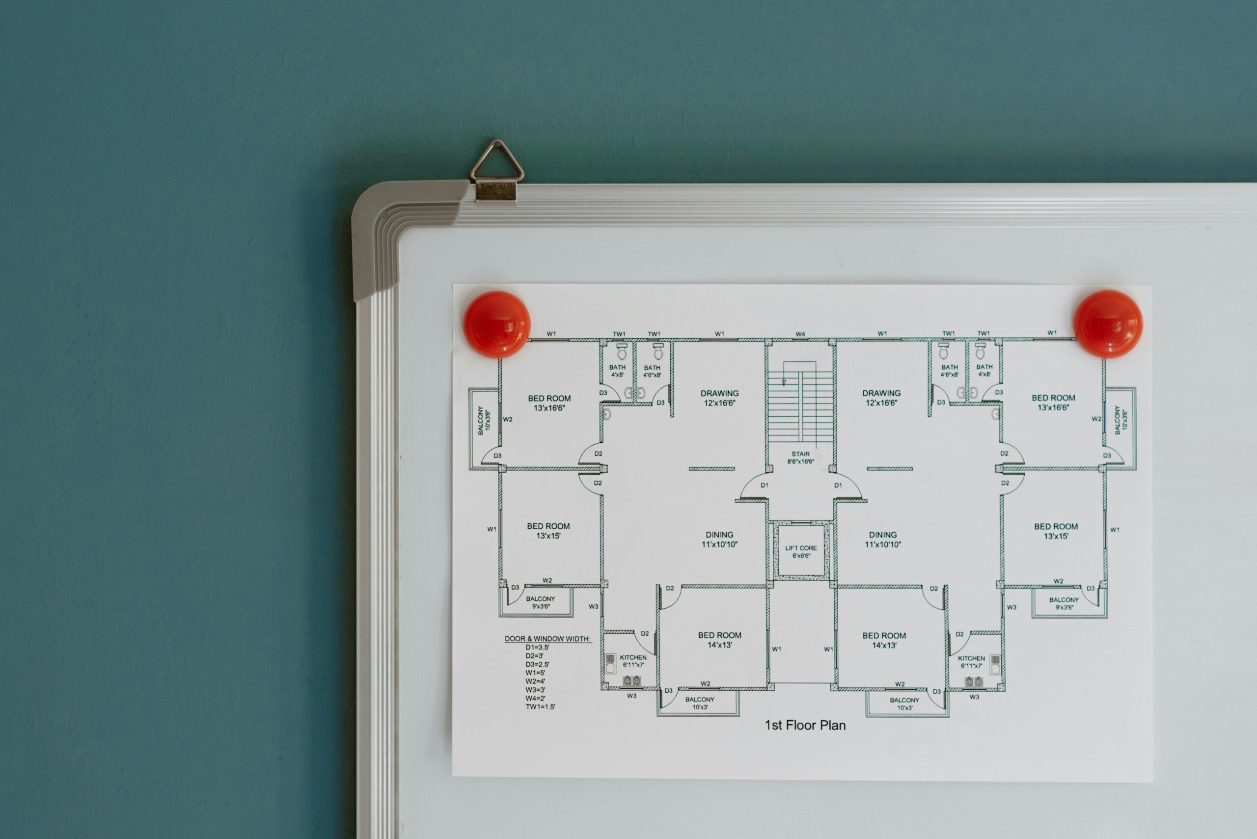 Detailed architectural floor plan pinned on a whiteboard with red magnets.